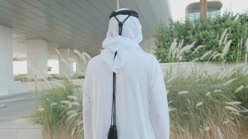 Portrait of Arab Emirati man wearing Kandura and Ghutra at a business location. Middle Eastern local doing crossed arms as he looks at the camera. Local UAE, Saudi, Qatar national concept Royalty-Free Stock Footage #1097095009