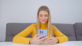 Beautiful Ukrainian girl browsing mobile app on cellphone. Cheerful blonde female communicating online with modern smartphone
