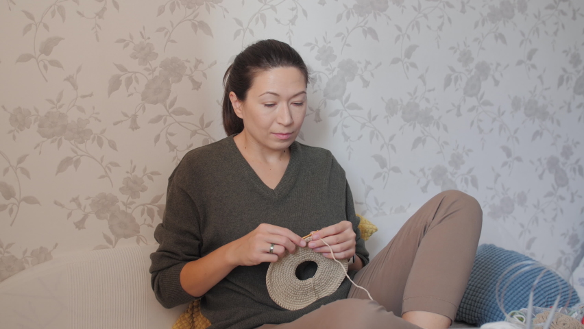 Close-up video of woman learning to crochet. Felt basket with balls of yarn. Anti-stress hobby. Online lessons for amateurs on laptop.