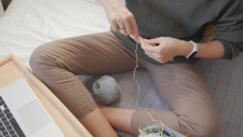 Close-up video of woman crocheting bag of polyester cord. Anti-stress hobby. Tranquil leisure at home. Handicraft. Online lessons for amateurs on laptop.