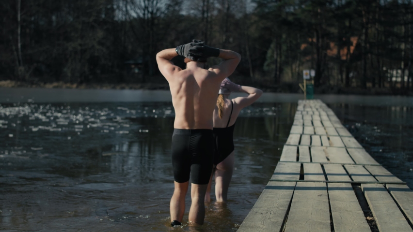 Rear view of caucasian man and woman going into a frozen lake. 