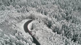 Drone footage. Winter landscape. Mountain road in snow-covered dense forest.