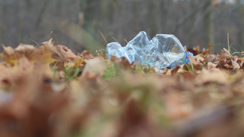 
A man picking up a plastic bottle and putting it in a blue garbage bag in the park. The concept of plastic pollution, forest cleaning.  | Shutterstock HD Video #1097125573