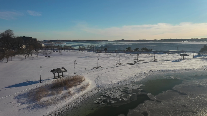 Aerial shot after snowstorm next to ocean with sunshine and blue skies
