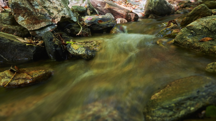 Babbling brook flowing along a rocky creek bed in autumn - long exposure time lapse