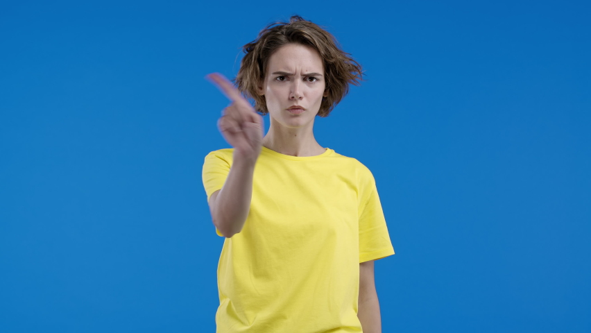 Dissatisfied woman disapproving with no finger warning sign, making negation gesture. Denying, rejecting, disagree. Portrait of young lady on blue background. | Shutterstock HD Video #1097134933