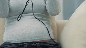 4k slow motion video of pregnant woman with headphones on stomach.