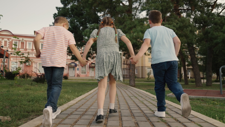Boy girl run along sidewalk, rest, have fun in nature. Children go for walk together. Child Friends run through city park holding hands. Happy people. Children play outdoors. Teamwork of children