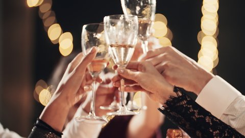 Happy festive group of friends drinking alcohol celebrating Christmas New Year waving sparklers. Close up hands cheers champagne clinking glasses. Smiling multiethnic people at Christmas eve night.: stockvideo