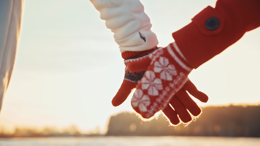 Back view of couple holding hands wearing gloves at winter sunset. Happy couple dating at sunny day outside at Christmas holidays. spend time together at Christmas eve. Girl and a guy have fun laugh | Shutterstock HD Video #1097141073