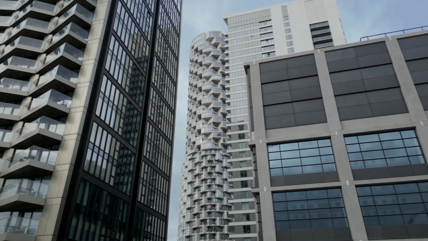 Drone shot flying and looking up at tall glass skyscrapers in England