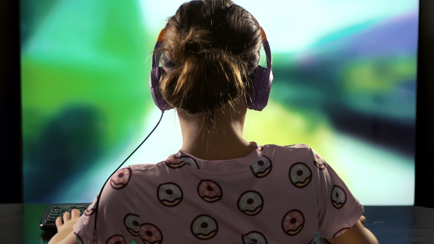 A child or teenager is playing an unrecognizable computer video game on a large blurry screen. Online video game technology and teen gambling addiction to video games | Shutterstock HD Video #1097150901