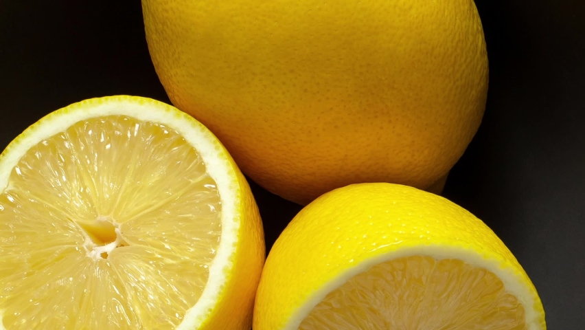 Lemons whole and cut in grey bowl, rotating, turning, close-up macro, top view
