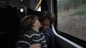 Son kissing father on cheek while traveling by train. Parent and child passengers inside moving high speed train. Kid showing love and affection - Powered by Shutterstock - Get 15% off with code: PIKWIZARD15