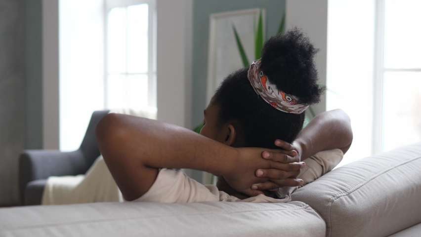 A young, peaceful African-American woman is resting on the couch with her eyes closed after a hard day's work. The concept of rest and tranquility. High quality 4k footage | Shutterstock HD Video #1097156443