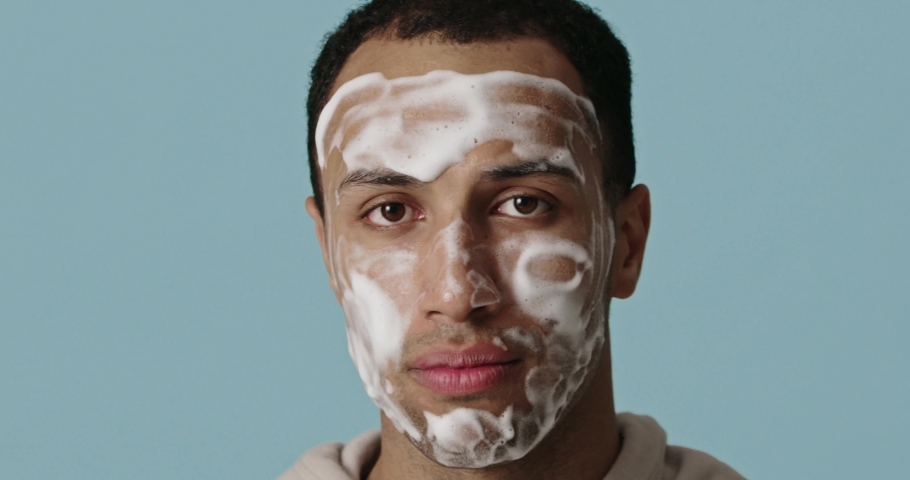 Face skin care. Multiracial man cleaning facial skin with foam soap. Happy guy cleansing face applying facial cleanser closeup. High resolution  | Shutterstock HD Video #1097159373