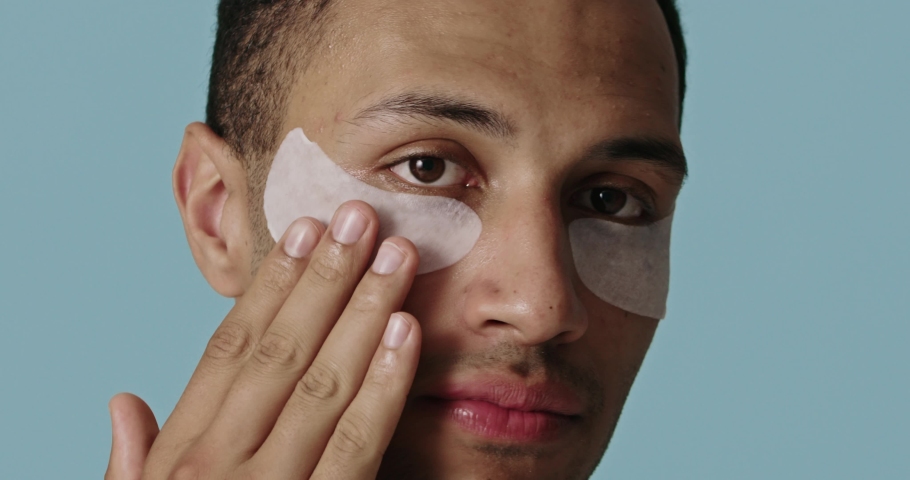 Skin care. Portrait of male model applying under eye patches. Beauty cosmetic mask on face. Face care routine. Cosmetology facial treatment  | Shutterstock HD Video #1097159387