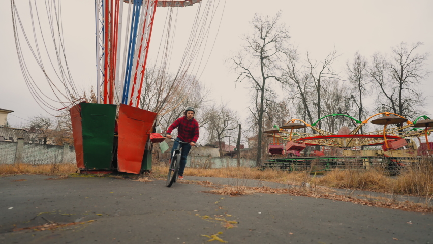 teenage boy is practicing flips on bmx bike in park, slow motion shot, beginner stunt rider