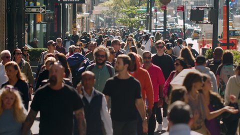 Редакционное стоковое видео: New York City, October 2022. United States. Crowd of Commuters, and Tourists Walking on Manhattan Avenue. Slow Motion Backlit Shot of Walking People Enjoying The City.