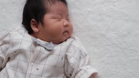 A video of a 1-month-old, 0-year-old newborn sleeping on the left side