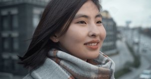 Beautiful Asian young woman looking at the camera and smiling. Portrait of a young woman on the background of the road and moving cars. Slow motion