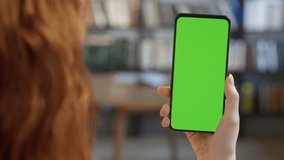 Back View of Woman Holding Chroma Key Green Screen Smartphone Watching Content Without Touching or Swiping. Female Using Mobile Phone, Browsing Internet, Watching Content, Videos, Blogs.