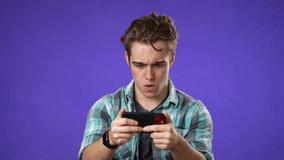 Playing game on phone smiling young man 20s in shirt play racing on mobile cell phone hold smartphone for pc video game isolated on blue background studio portrait