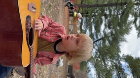 Portrait of adorable 5 years old caucasian boy with blue eyes playing with guitar strings in the park. Summertime. Natural light. Vertical mobile phone video orientation.