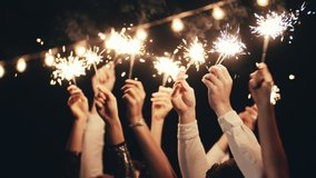 close up hands holding sparklers group of friends celebrating Christmas waving sparkler fireworks dancing enjoying new years eve party having fun holiday celebration at evening Christmas gathering. - Powered by Shutterstock - Get 15% off with code: PIKWIZARD15