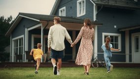 Young Beautiful Couple Walking Outdoors Towards the Country House, Holding Hands. Their Little Son and Daughter Running Together with Them. Young Modern Family at Home, Footage from The Back. - Powered by Shutterstock - Get 15% off with code: PIKWIZARD15
