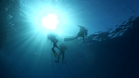 scuba diver silhouette  exploring  underwater deep blue water bubbles ocean scenery with sun beams and rays