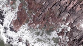 Top down view on waces breaks on rocks on sunset. High quality 4k aerial drone footage