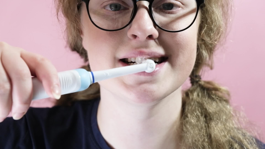 Close Up Of Woman Brushing Teeth With Electric Toothbrush pink background | Shutterstock HD Video #1097190781