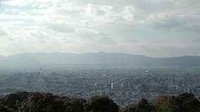 KYOTO, JAPAN - DEC 2021 : Aerial panoramic view of Kyoto city in daytime. Scenery of mountain, streets and buildings around downtown area. Japanese nature and traditional old town concept video.