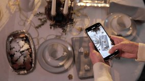 Woman hands shooting Christmas table setting on smartphone for her social media blog. Blogger vlogger
