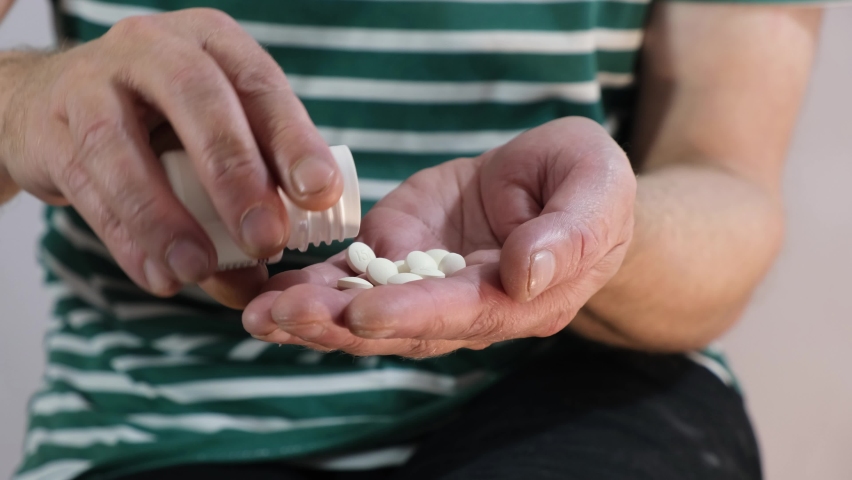 A man pours pills for insomnia into his palm, a senior man suffers from insomnia and takes medication 4k | Shutterstock HD Video #1097192867