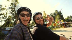 Young Mixed Raced Tourist Couple Riding Motorbike in Asia and Taking Funny Selfie Videos Using Action Camera High Quality 4K Slowmotion Footage. Thailand.