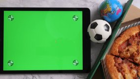 Top view of tablet with green screen display, pizza and balls on the table. - Powered by Shutterstock - Get 15% off with code: PIKWIZARD15