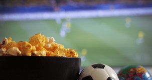 Close-up shot of a man eating popcorn while watching a football match in the living room.