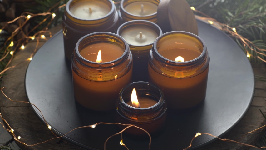Soy candles burn in glass jars. Comfort at home. Candle in a brown jar. Scent and light. Scented handmade candle. Aroma therapy. Christmas tree and winter mood. Cozy home decor. Festive decoration.