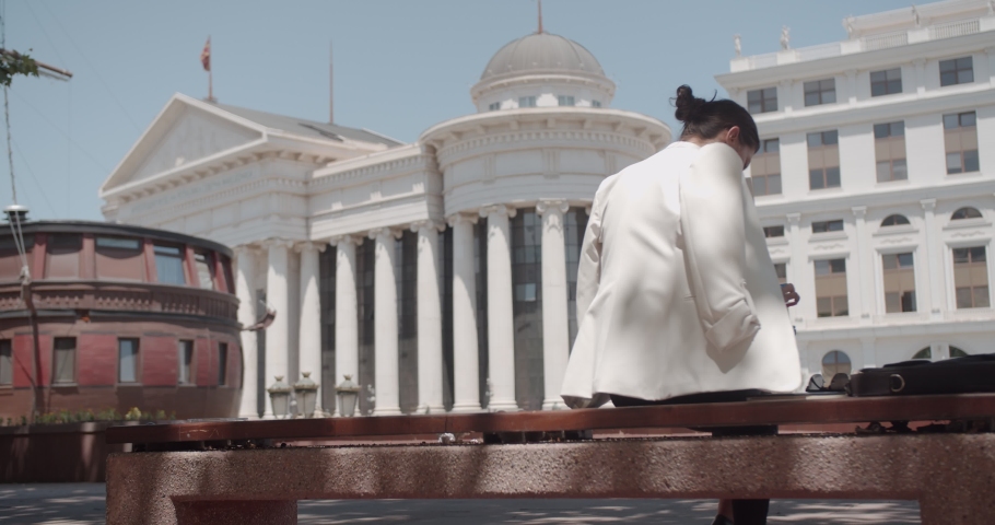 Business lady making notes while sitting at a bench, downtown area