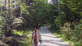 Slow motion video of a black woman with backpack hiking alone through the forest.
