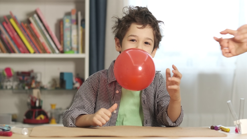 Boy releases an inflated balloon from his teeth. Balloon deflates, flies away. scientific experiment. observing physical phenomena and staging various physical experiments. | Shutterstock HD Video #1097205483