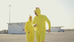 Cinematic video of a couple having fun wearing a chicken pajama costume outdoor. Man and woman celebrating outside. Representation of carefree concept