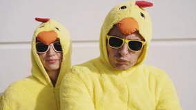 Cinematic video of a couple having fun wearing a chicken pajama costume outdoor. Man and woman celebrating outside. Representation of carefree concept