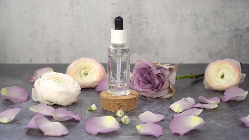 Cosmetic pipette with natural perfume. Organic natural liquid cosmetic in glass transparent bottle, roses flowers at the background, skin and body care concept. | Shutterstock HD Video #1097207509