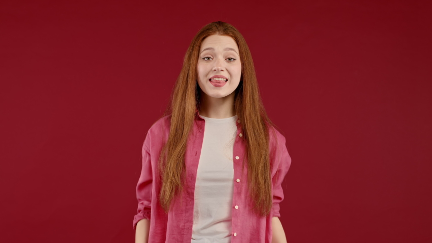 Shocked woman with ginger hair very glad, she screaming loud WOW. Lady trying to get attention. Concept of black friday sales, profitable offer. Excited happy girl on red background. | Shutterstock HD Video #1097208091