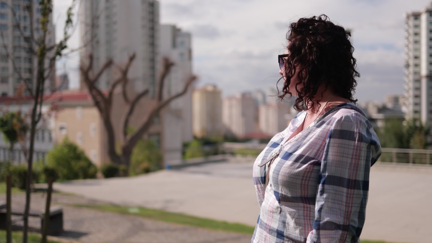 A brunette woman walks through the streets in the city on a summer sunny day