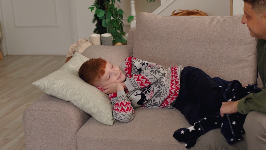 The father puts his son to sleep carefully covering him with a blanket. New Year | Shutterstock HD Video #1097211035