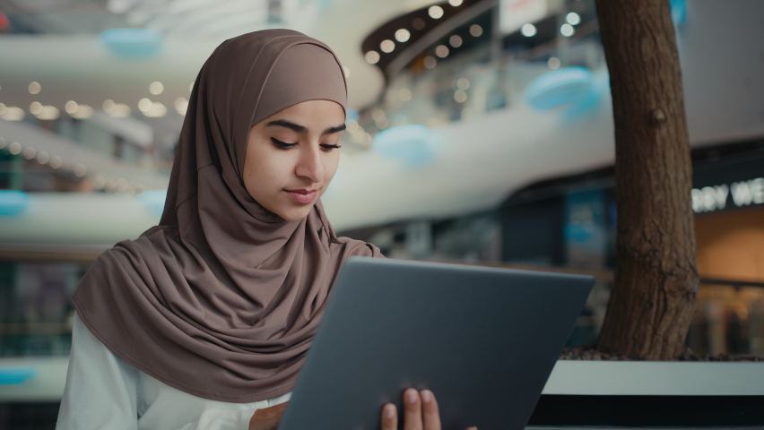Islamic arabian muslim businesswoman in hijab female entrepreneur student girl woman working at shopping mall use laptop browsing internet search job vacancy make order buying online learning distant  | Shutterstock HD Video #1097212651